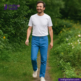 Man walking on a path in a green, natural setting with 'Indigo Tailor' branding. wearing AOZORA SKY BLUE DENIM jeans