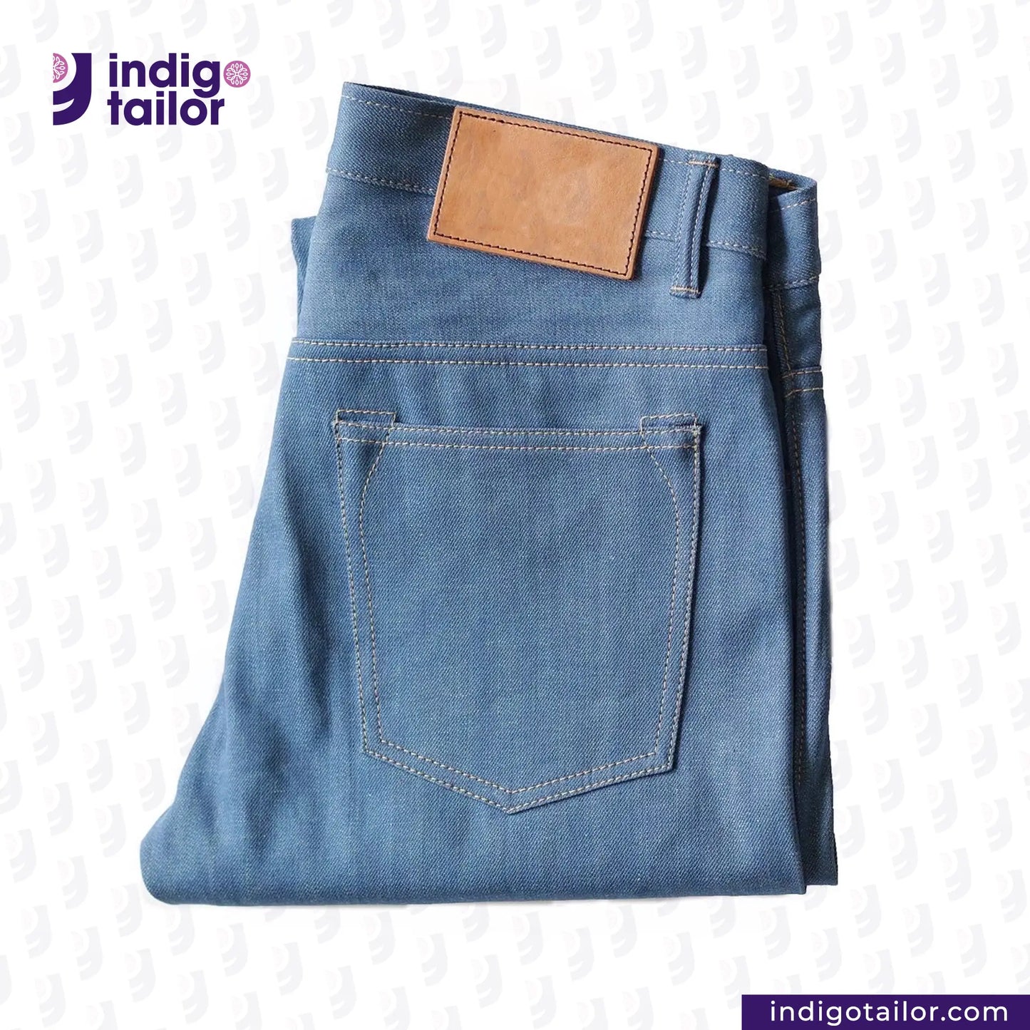 Folded AOZORA SKY BLUE DENIM jeans with a brown patch on a light gray background, featuring the Indigotailor logo.