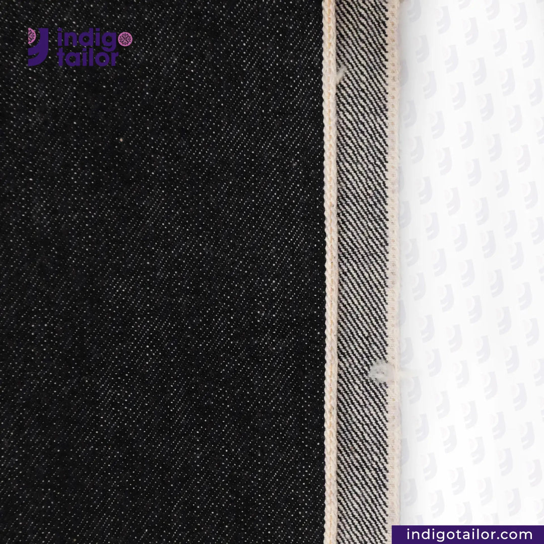 Close-up of BLACK SLUBBY SELVEDGE DENIM fabric with a white background, featuring the Indigotailor logo.