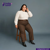 Woman wearing a white blouse and brown pants sitting on a stool with Indigotailor logo in the corner. Brown SOFT SLUB SELVEDGE DENIM