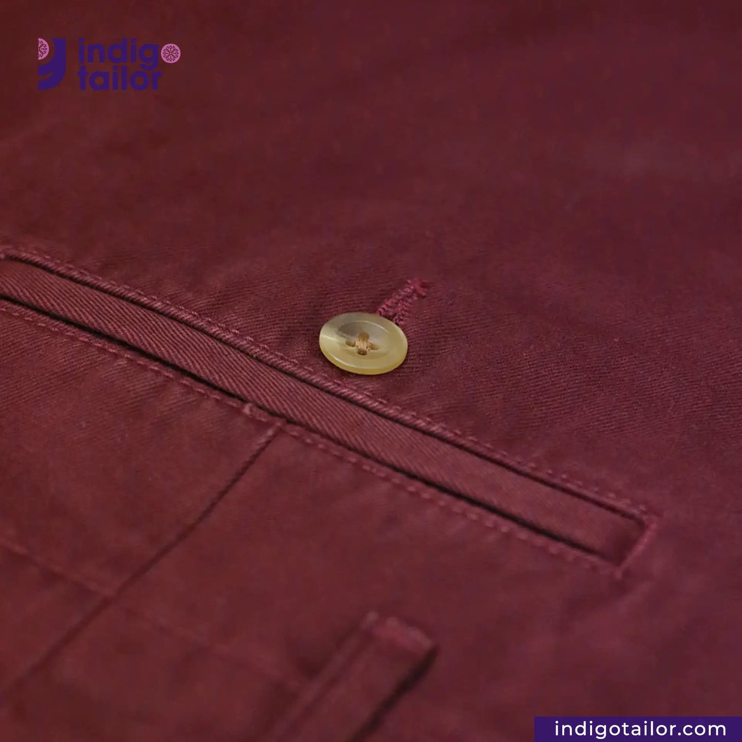 Close-up of a Chino Burgundy fabric with a button, featuring the Indigotailor logo.