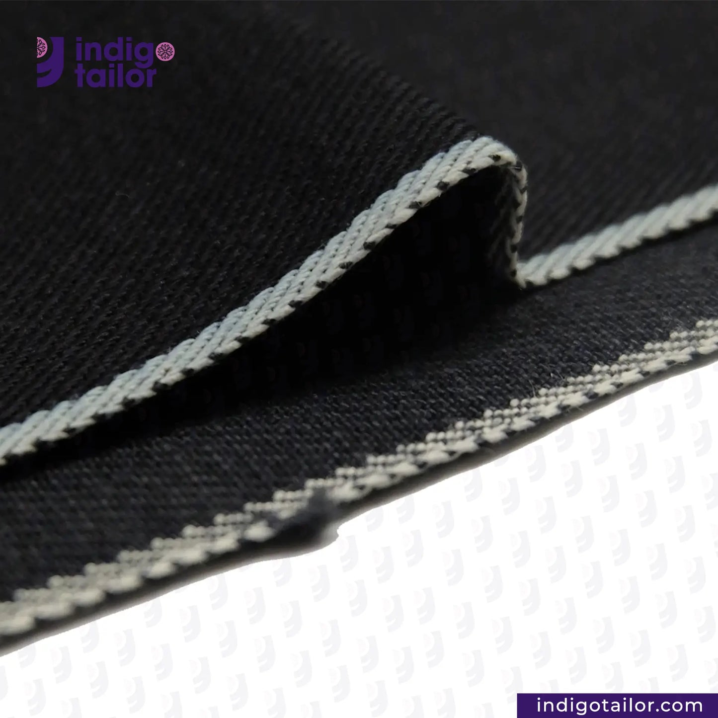 Close-up of DARK INDIGO x BLACK SELVEDGE DENIM fabric with white stitching, featuring the Indigotailor logo.
