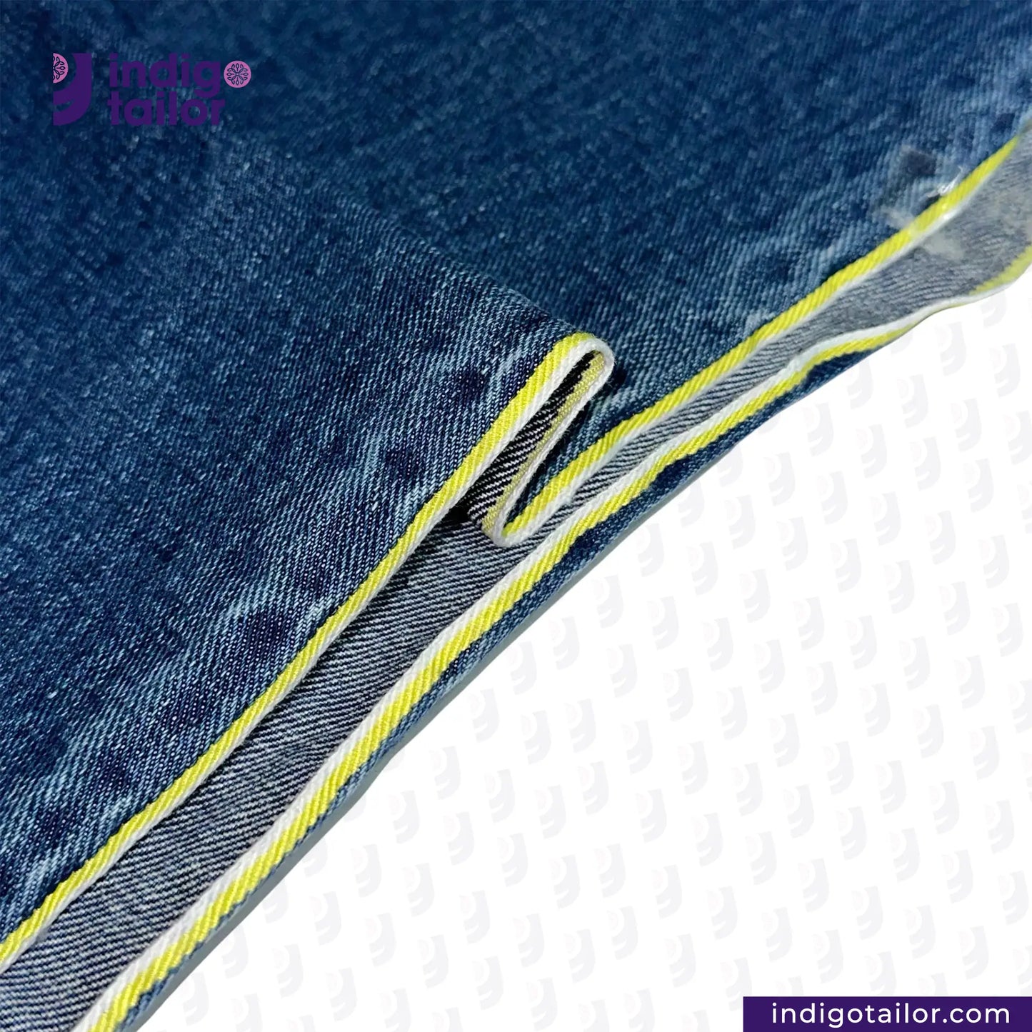 Close-up of DARK WASHED SELVEDGE DENIM LIME SELVEDGE ID fabric with yellow stitching on a white background, featuring the Indigo Tailor logo.