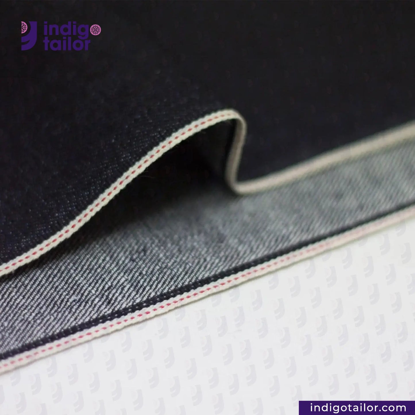 Close-up of DEEP INDIGO STRETCH SELVEDGE DENIM fabric with 'Indigotailor' branding on a dark background