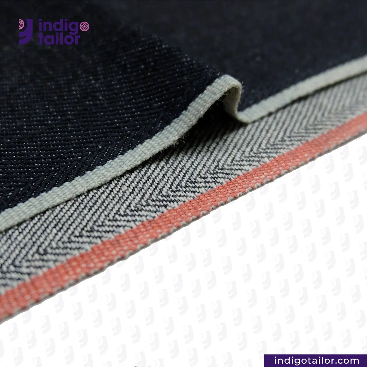 Close-up of DEEP INDIGO TWO COLORED EDGE SELVEDGE DENIM fabric with a visible brand logo, showing texture and color details.