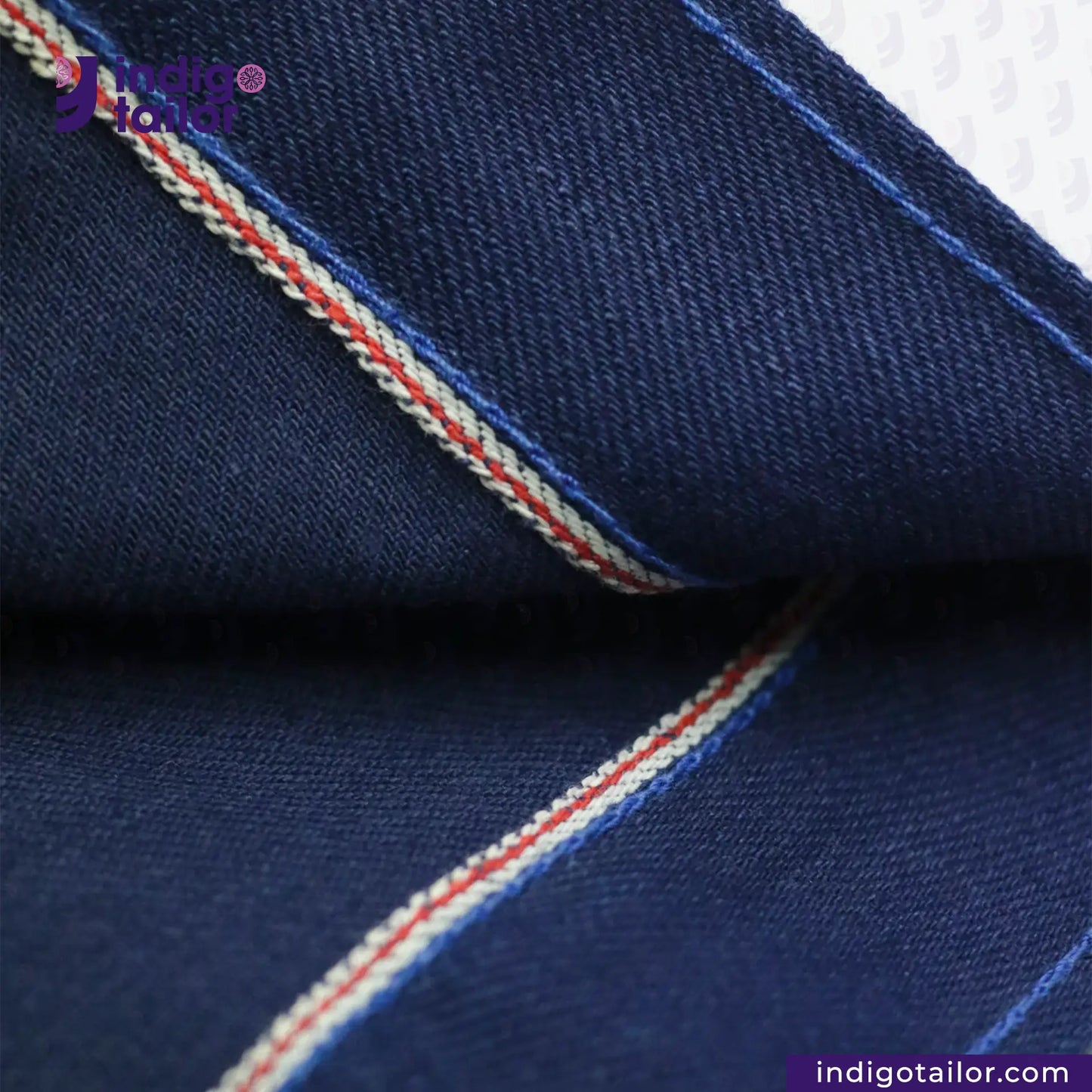 Close-up of DOUBLE DIPPED TRIPLE PLEAT REPRO fabric with red and white stitching, featuring Indigotailor logo.