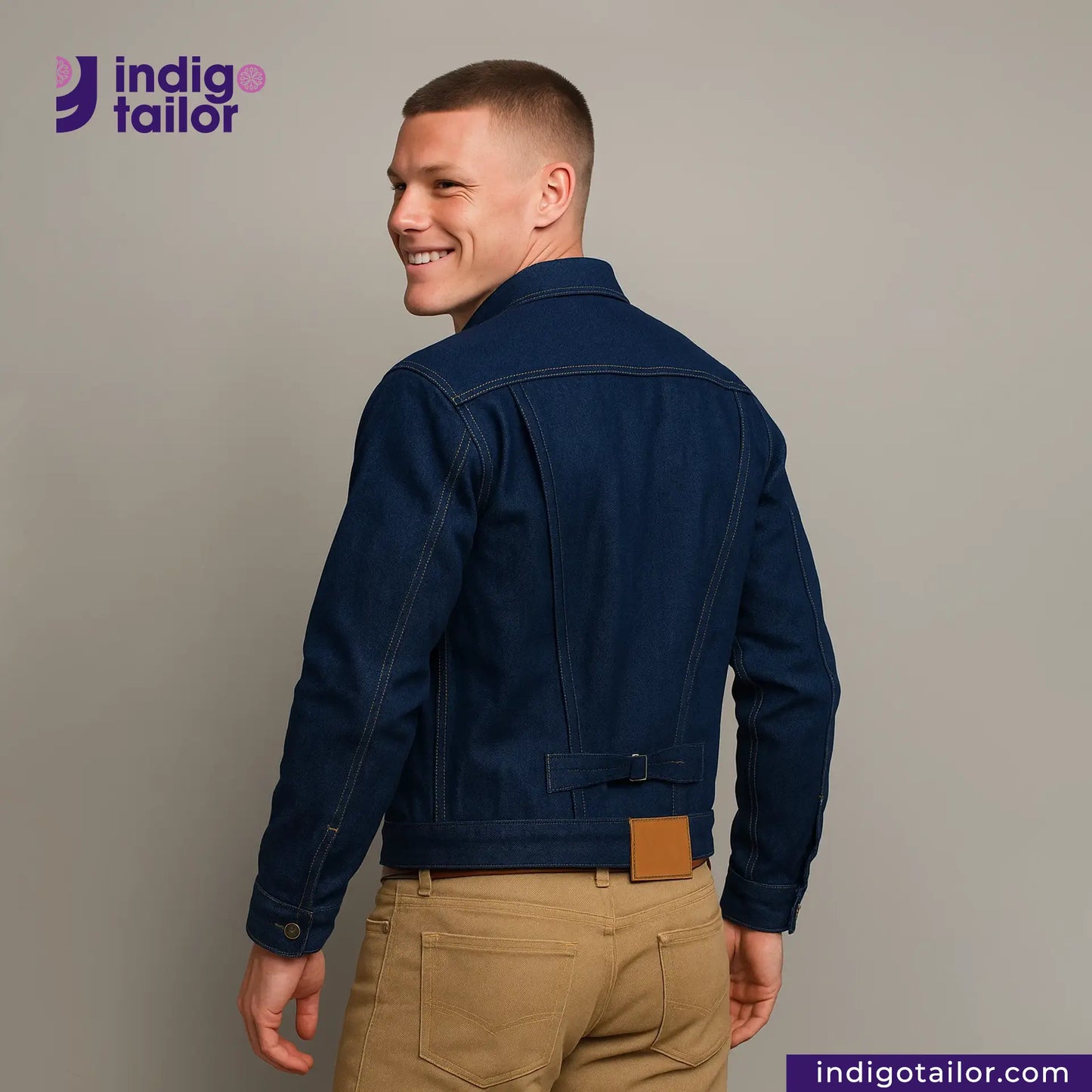 Man wearing a DOUBLE DIPPED TRIPLE PLEAT REPRO denim jacket with 'Indigo Tailor' logo and website on a gray background