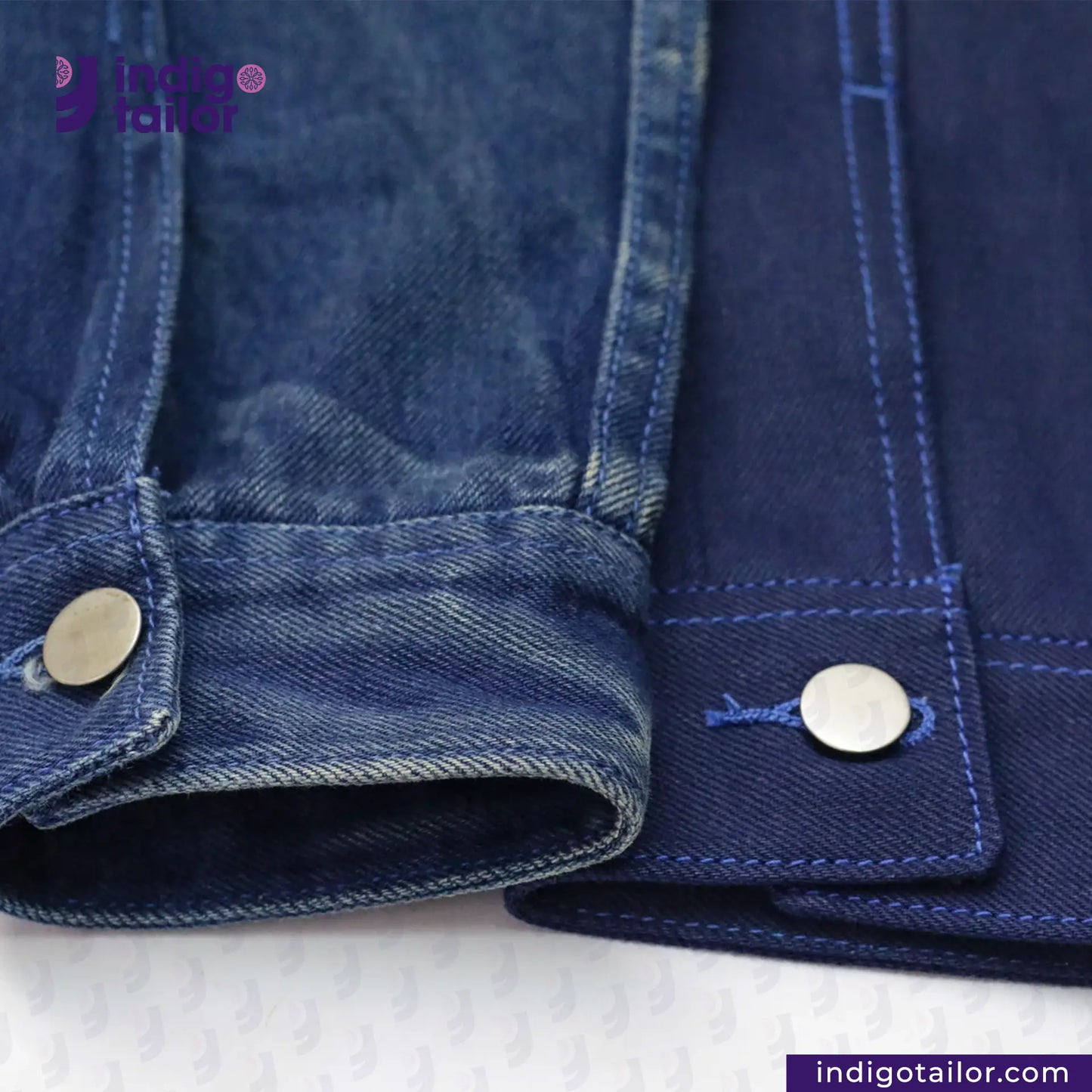 Close-up of a DOUBLE DIPPED TRIPLE PLEAT REPRO denim jacket with buttons on a white background, featuring the Indigo Tailor logo.