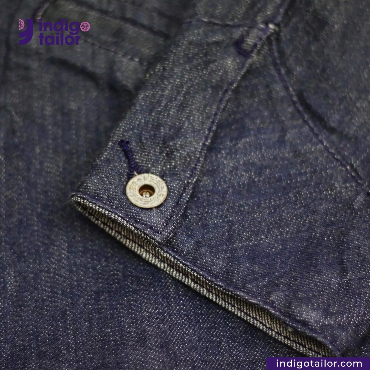 Close-up of a button on a FLIGHT JACKET with 'Indigotailor' branding.