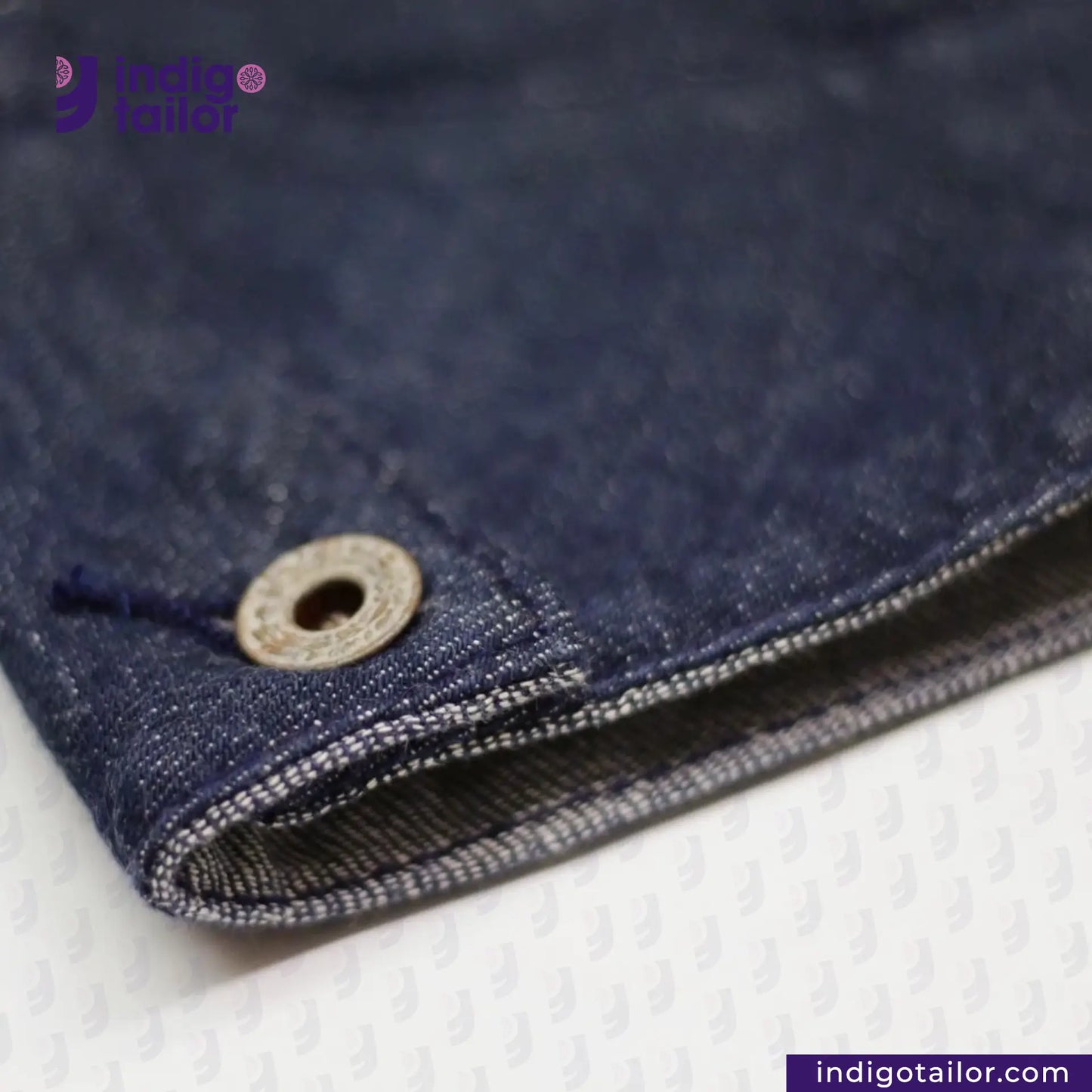 Close-up of FLIGHT JACKET with a button, featuring 'indigotailor' branding.