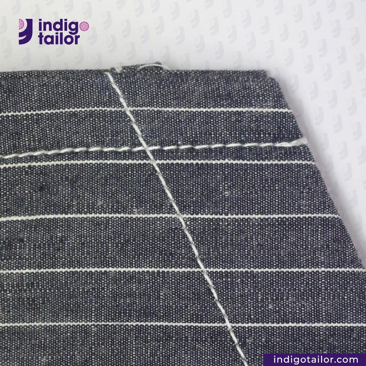 Close-up of INDIGO VINTAGE STRIPE WORK VEST with white stitching on a textured white background, featuring the Indigotailor logo.