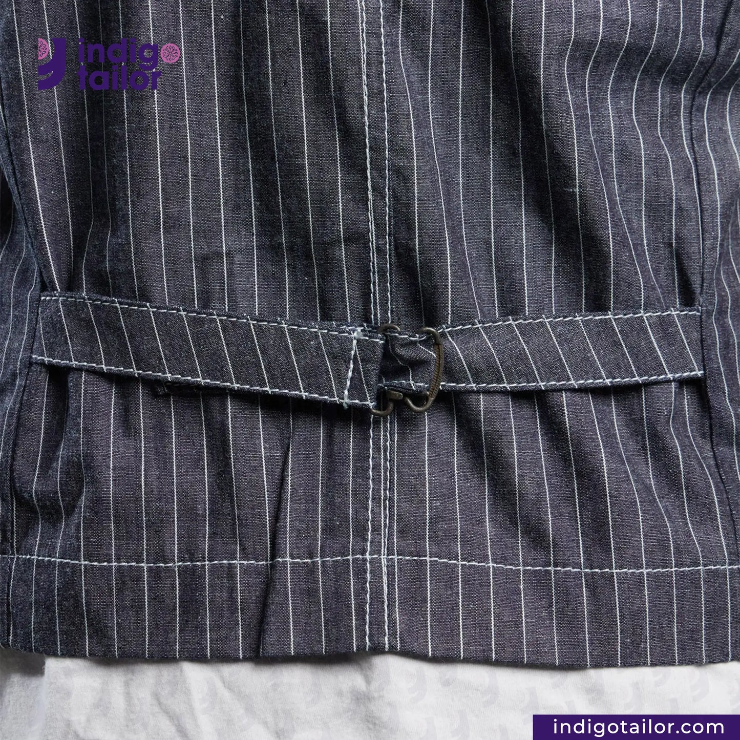Close-up of a INDIGO VINTAGE STRIPE WORK VEST garment with a belt, featuring the Indigo Tailor logo.