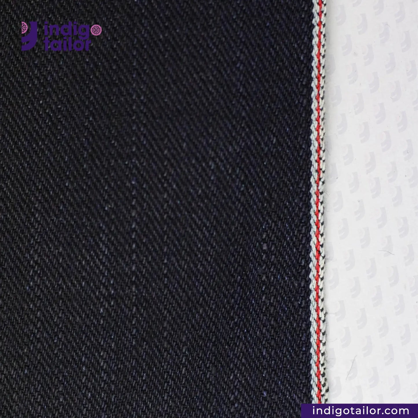 Close-up of black, INDIGO X BLACK SELVEDGE DENIM fabric with Indigo Tailor logo and website.