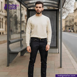 Man standing at a bus stop wearing a white sweater and black pants, with 'Indigotailor' branding.