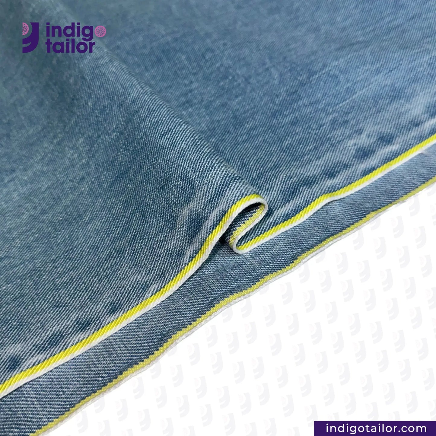 Close-up of LIGHT WASHED SELVEDGE DENIM LIME SELVEDGE ID fabric with yellow stitching on a white background, featuring the Indigotailor logo.