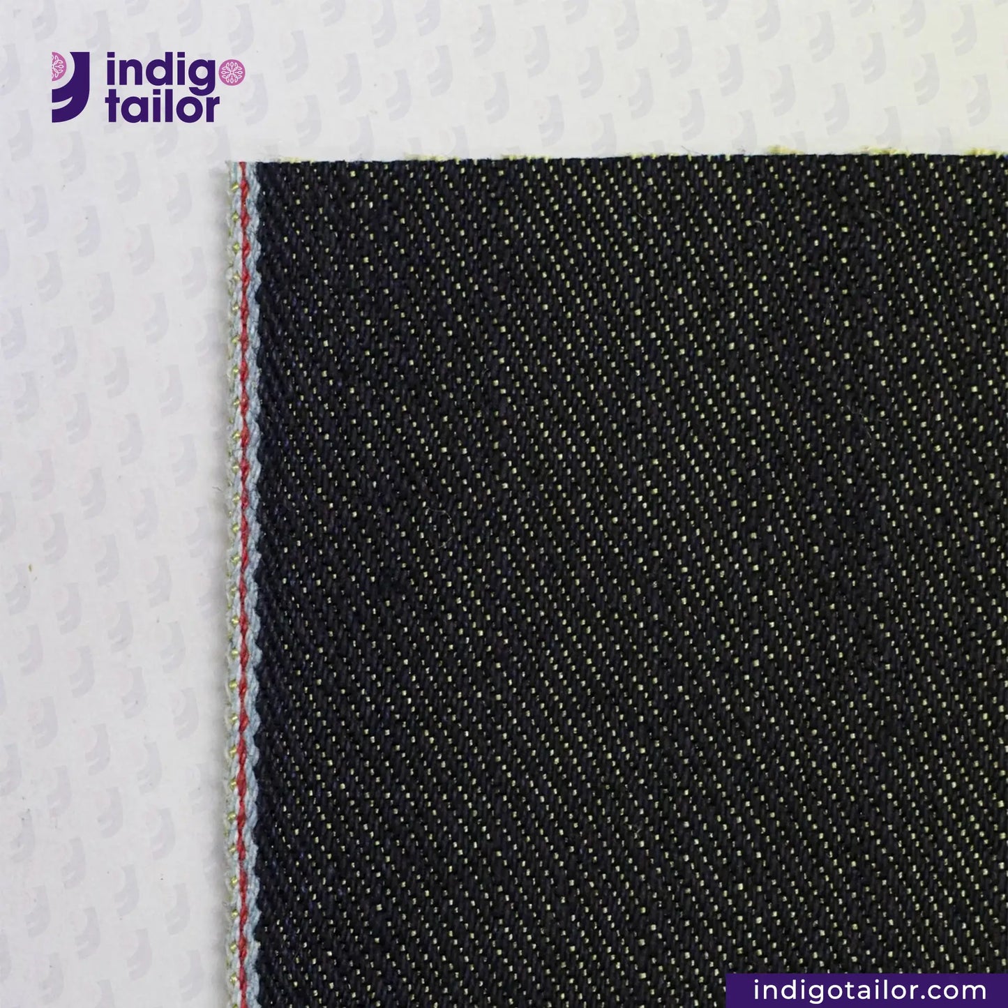 Close-up of METALLIC GOLD WEFT SELVEDGE DENIM fabric with a visible brand logo in the corner.