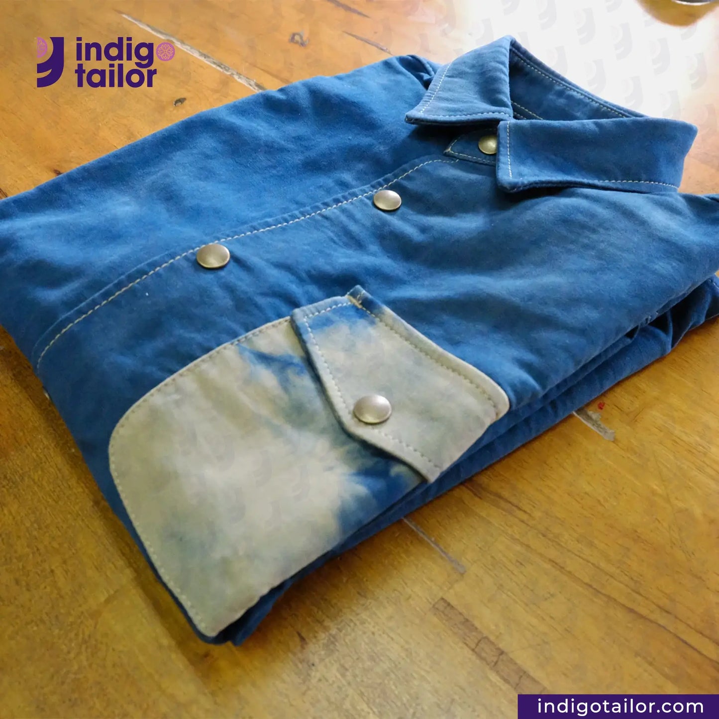 Folded NATURAL INDIGO DYED SUEDE jacket on a wooden surface with 'indigotailor' branding.