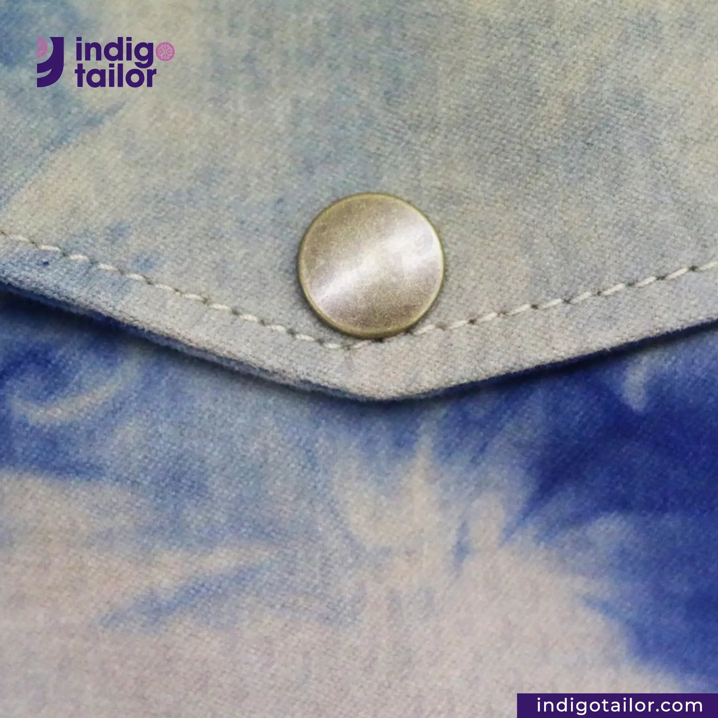 Close-up of a button on tie-dye NATURAL INDIGO SUEDE SHACKET with 'indigotailor' branding.