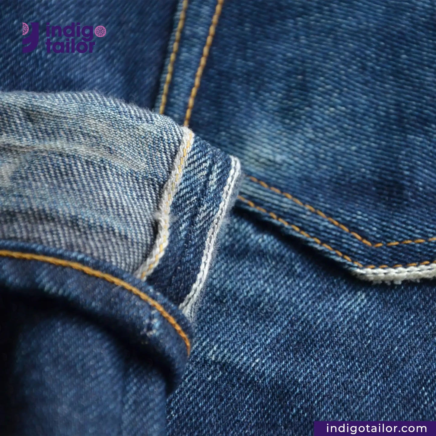 Close-up of blue denim fabric with stitching detail, featuring the Indigotailor logo.