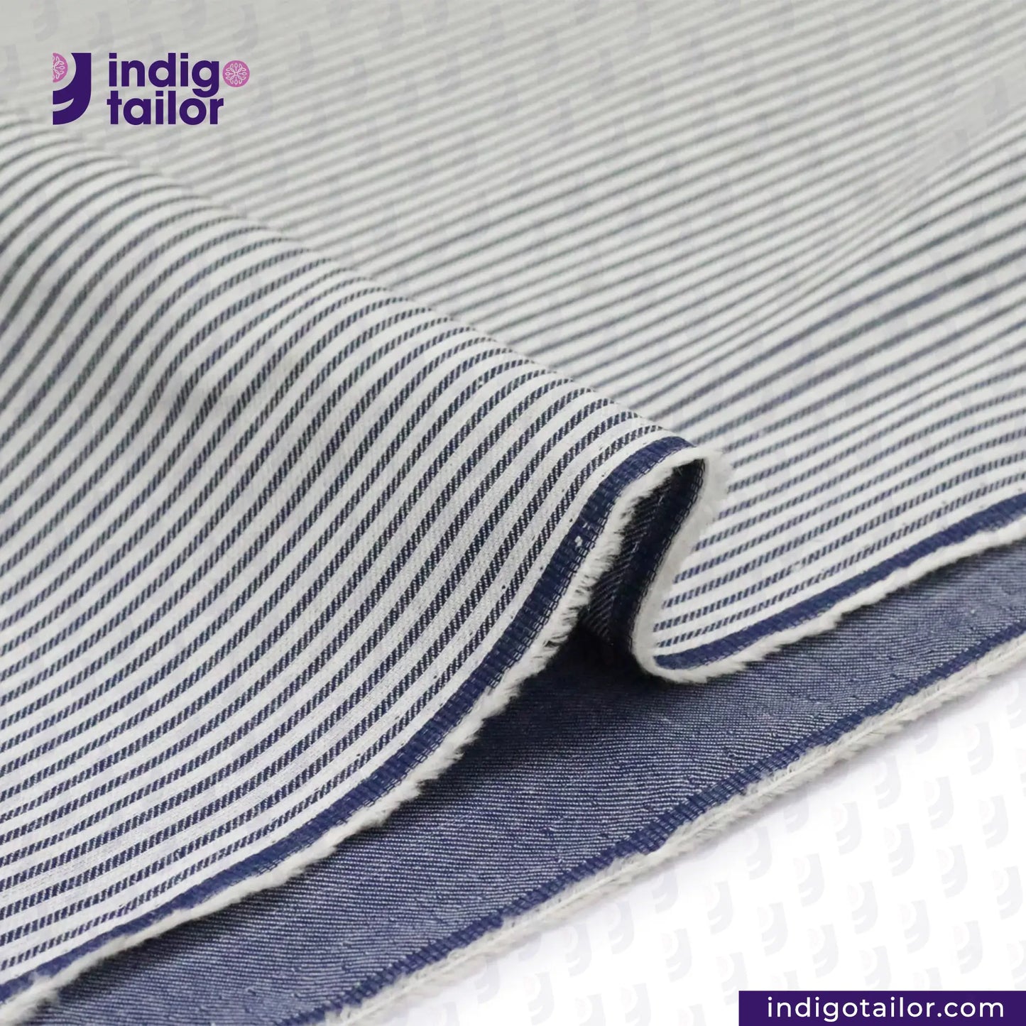 REVERSIBLE CHAMBRAY BLUE GREY WITH SUBTLE HICKORY STRIPES fabric with 'Indigotailor' branding on a white background