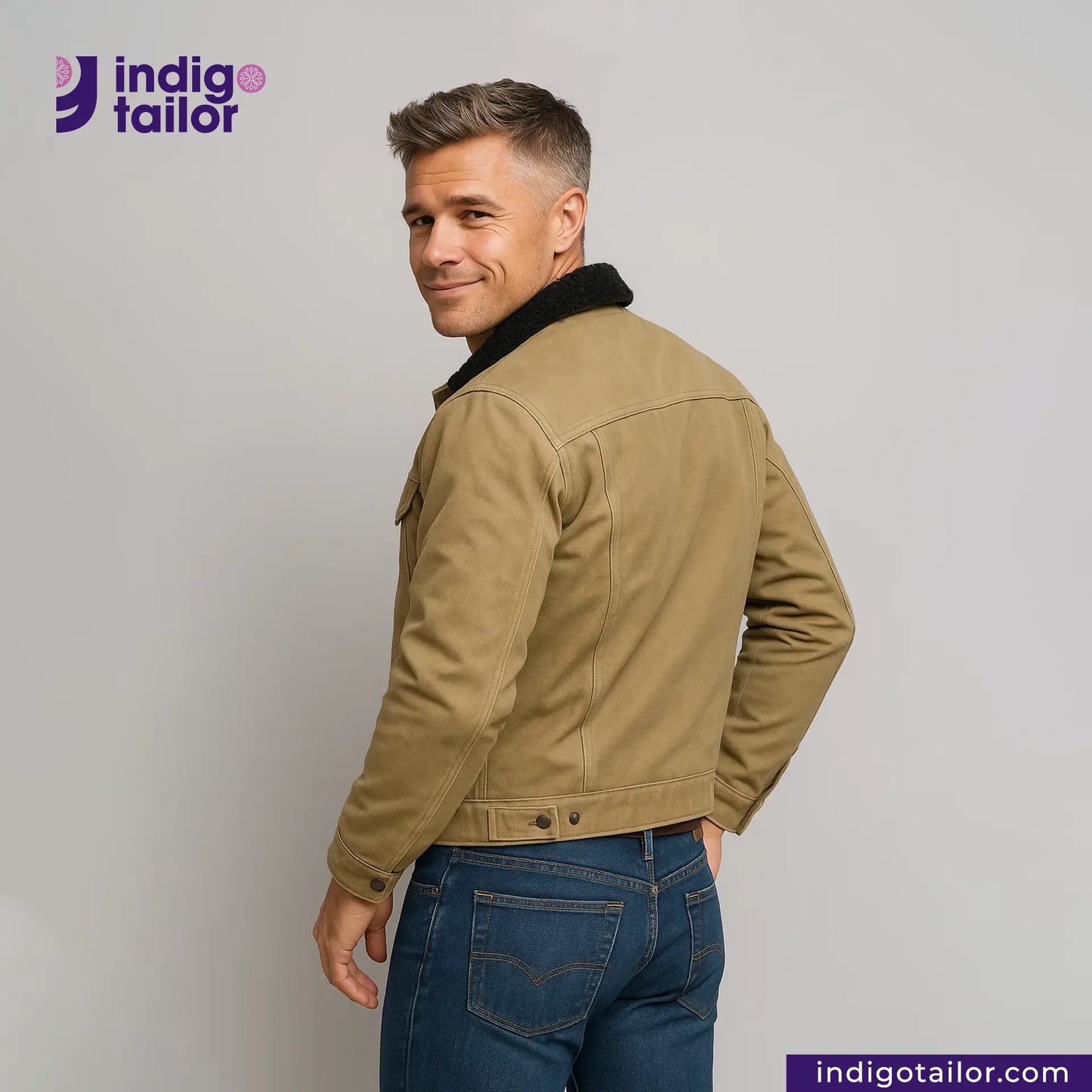 Man wearing a SHERPA LINED WAXED CANVAS TRUCKER JACKET and blue jeans with 'Indigo Tailor' logo and website on a gray background