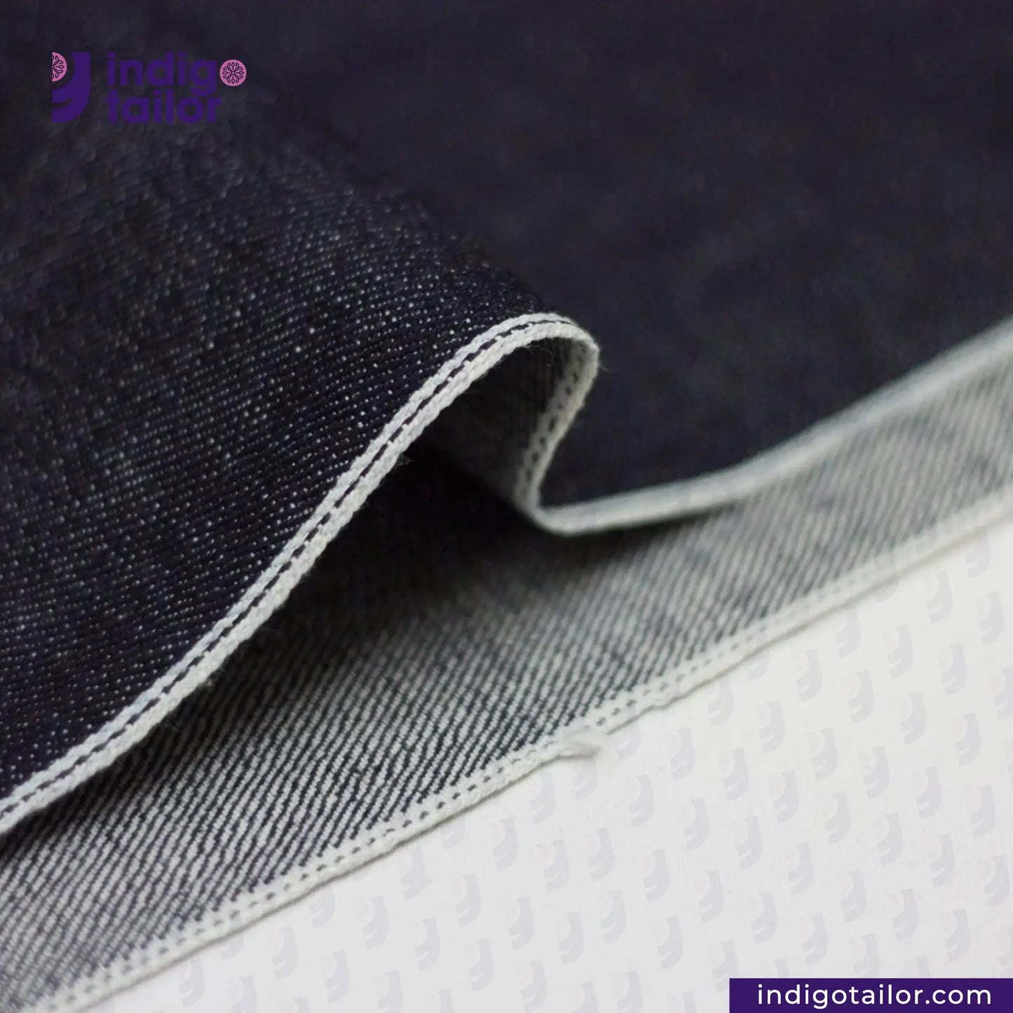 Close-up of SLUBBY INDIGO SELVEDGE DENIM fabric with 'Indigotailor' branding.