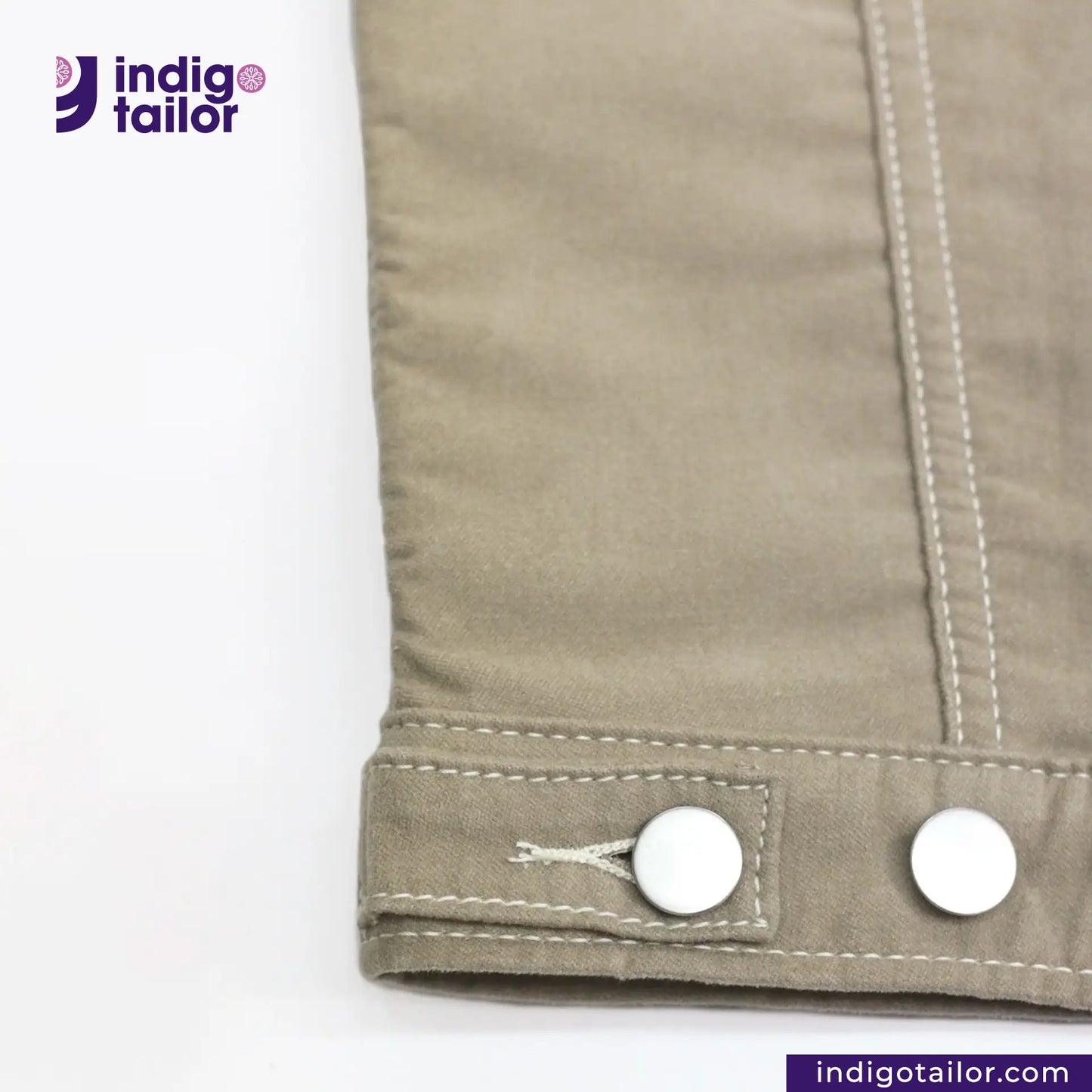 Close-up of a buttoned SUEDE JACKET cuff with 'Indigo Tailor' branding.