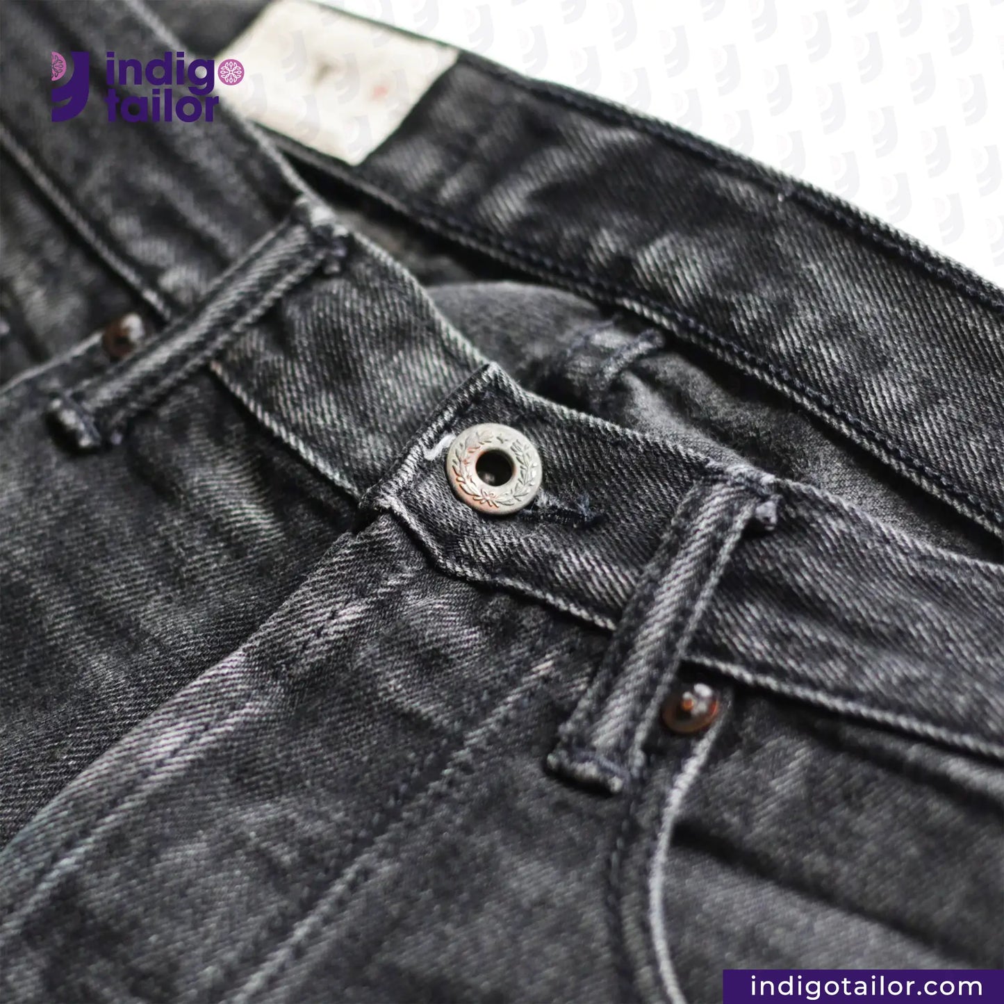 Close-up of SUPER BLACK DENIM jeans with a brand label on a white background