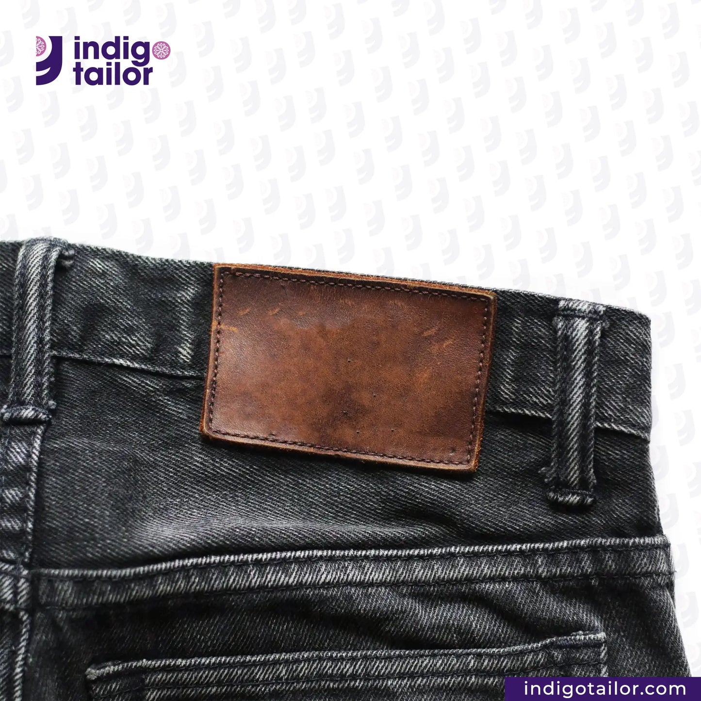Close-up of SUPER BLACK DENIM jeans with a brown leather patch on a white background, featuring the 'Indigotailor' brand.