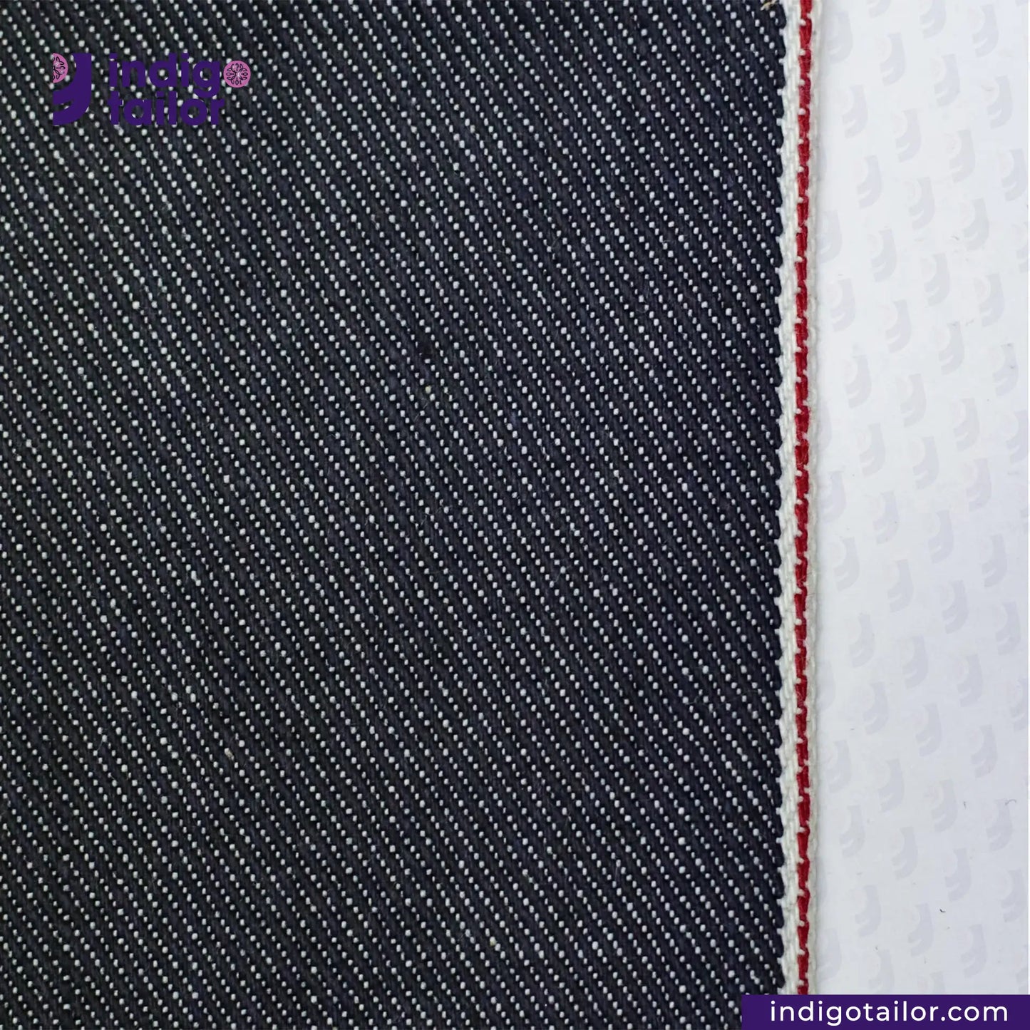 Close-up of SUPER SOFT FLUFFY SELVEDGE DENIM fabric with a white stripe and red stitching, featuring 'indigotailor' branding.
