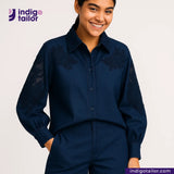 Woman wearing a TWO TONE SELVEDGE PAPER WEIGHT DENIM embroidered shirt and pants with 'Indigo Tailor' logo.