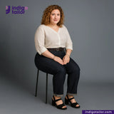 Woman sitting on a chair wearing a white blouse and TWO TONE SELVEDGE PAPER WEIGHT DENIM pants with Indigotailor logo in the corner.