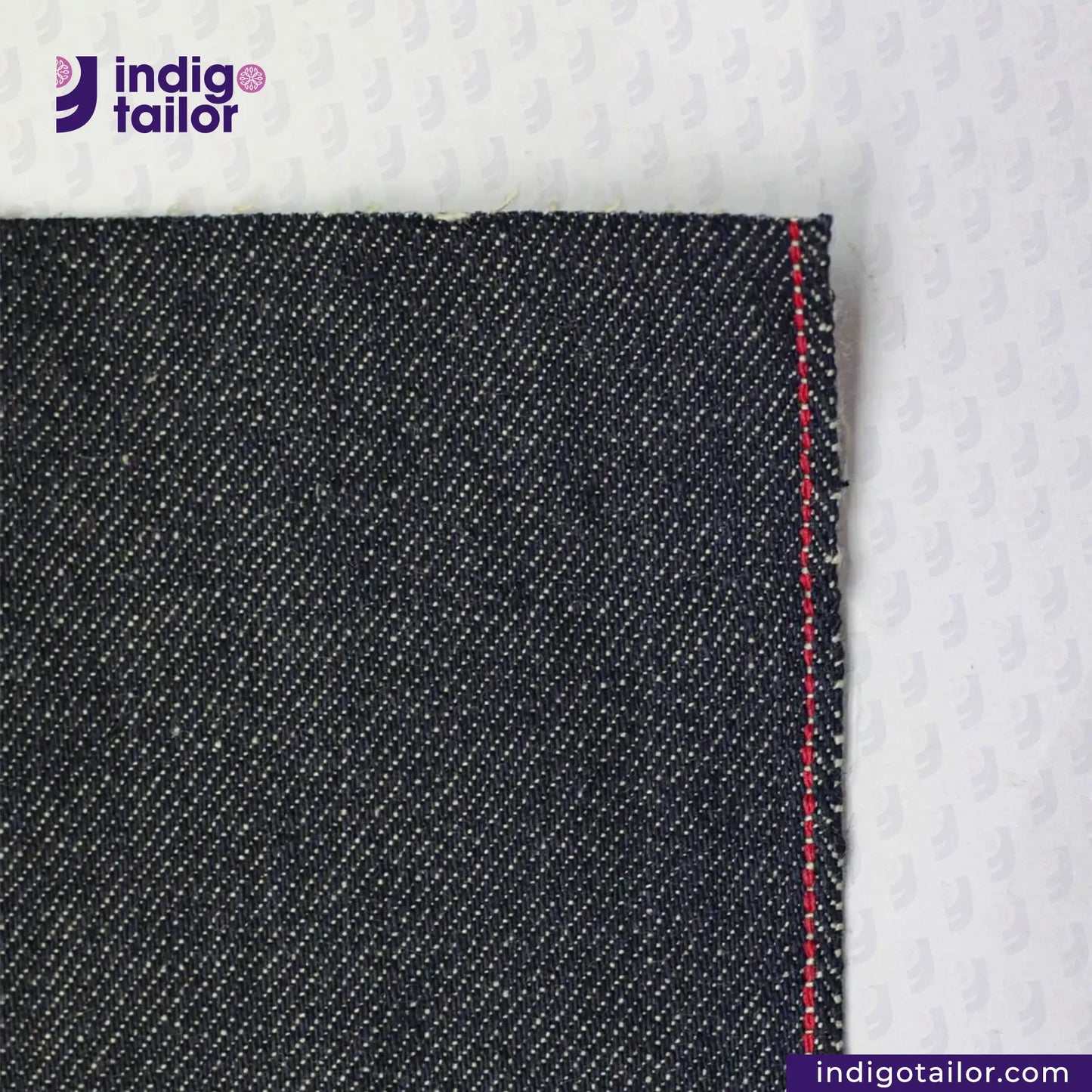 Close-up of UNSANFORIZED LOOM-STATE KIBATA DENIM fabric with a red stitch on a white background, featuring the Indigotailor logo.