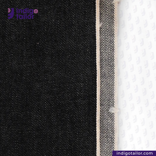 Close-up of BLACK SLUBBY SELVEDGE DENIM fabric with a white background, featuring the Indigotailor logo.