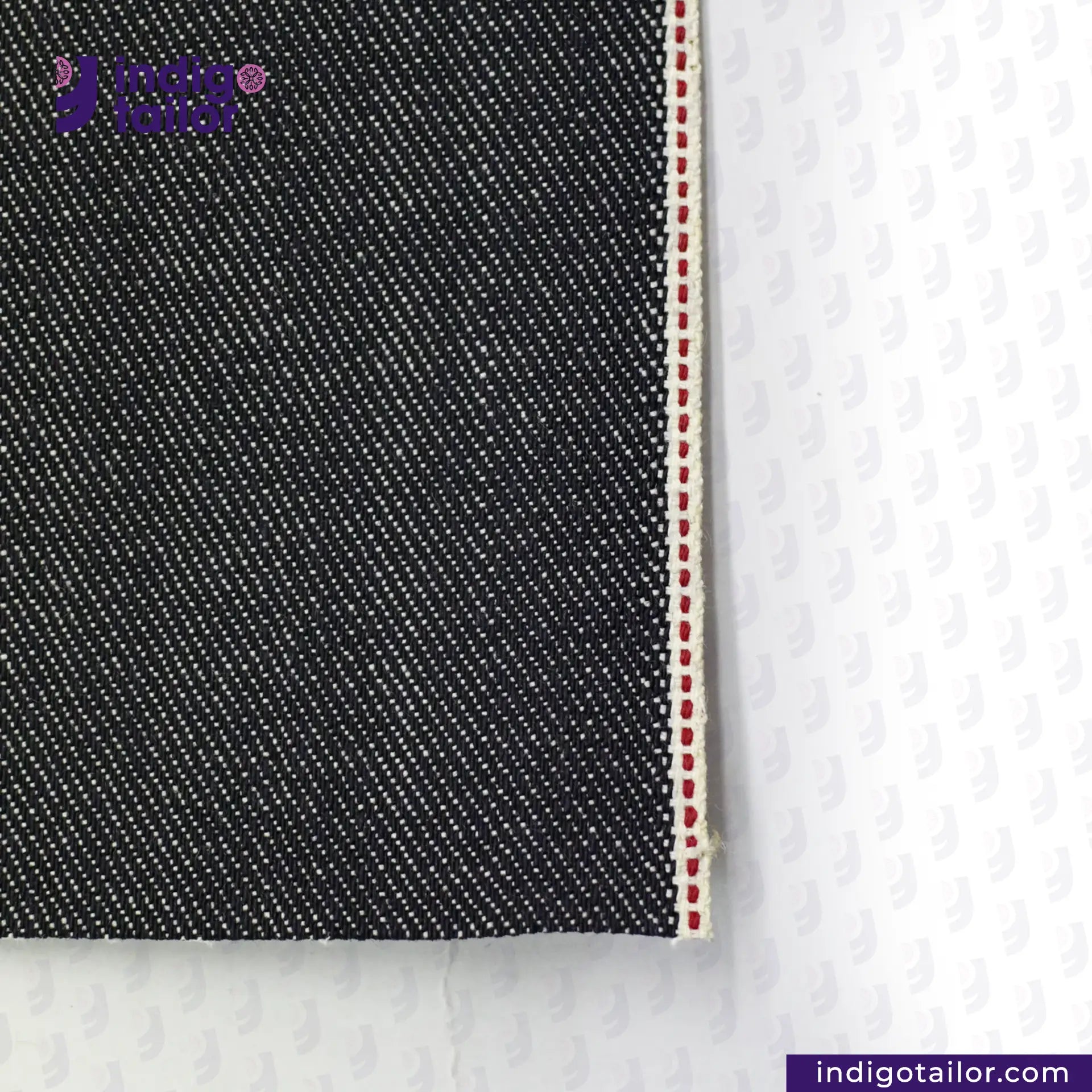 Close-up of BLUE GRAY SELVEDGE DENIM fabric with a white background, featuring the Indigo Tailor logo.