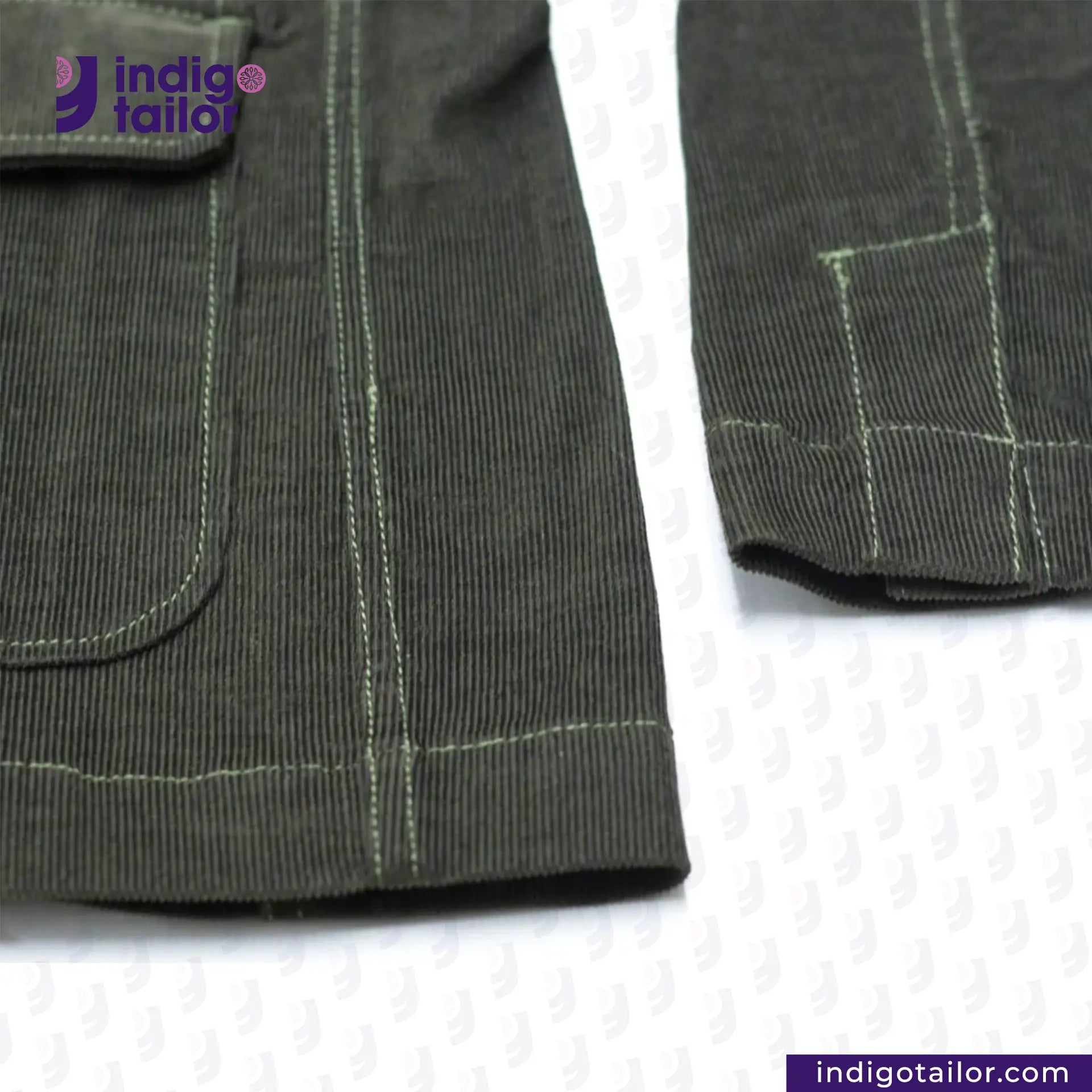 Close-up of CORDUROY CHORE BLAZER (OLIVE) fabric with stitching details on a white background, featuring the Indigotailor logo.