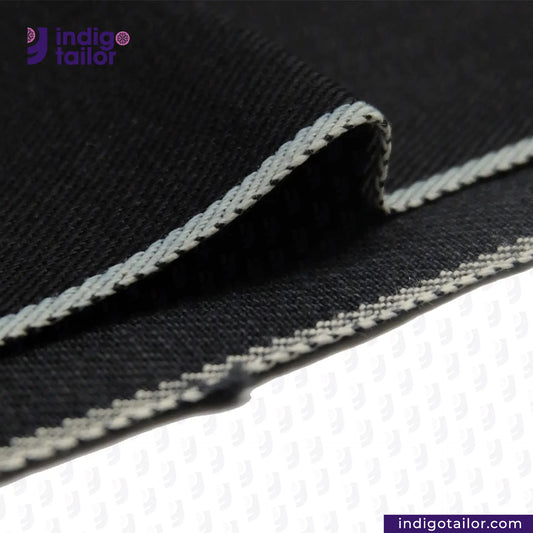 Close-up of DARK INDIGO x BLACK SELVEDGE DENIM fabric with white stitching, featuring the Indigotailor logo.