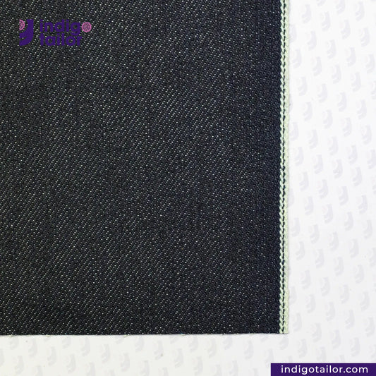 Close-up of DEEP INDIGO GREENCAST SELVEDGE DENIM fabric with a visible brand logo on a white background