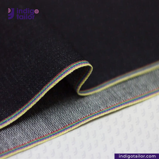 Close-up of DEEP INDIGO RAINBOW STRETCH SELVEDGE DENIM fabric with colorful stitching, featuring the Indigotailor logo.