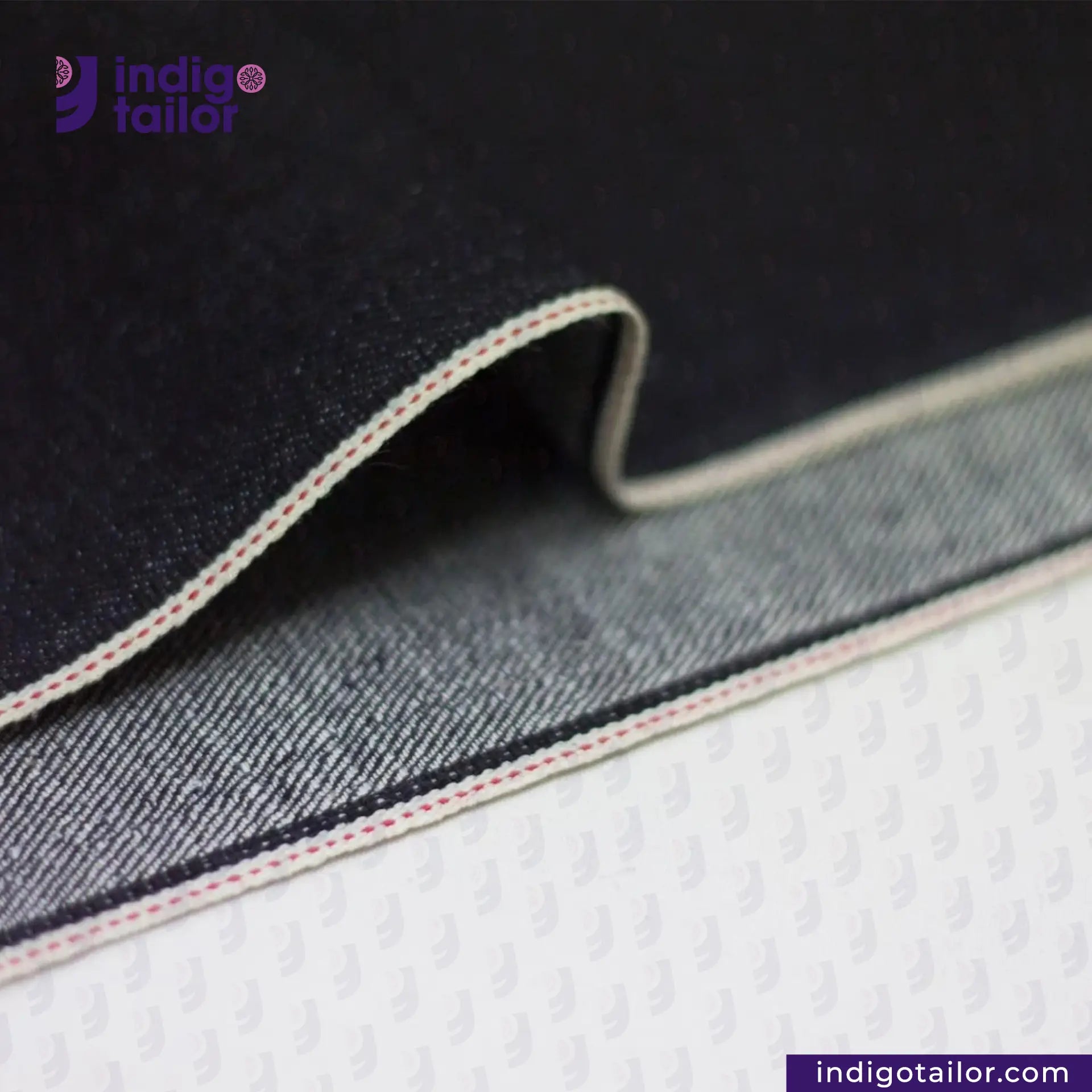 Close-up of DEEP INDIGO STRETCH SELVEDGE DENIM fabric with 'Indigotailor' branding on a dark background