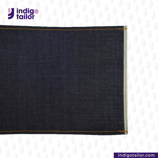 Close-up of DEEP INDIGO STRETCH SELVEDGE DENIM fabric with 'Indigo Tailor' logo and website URL.