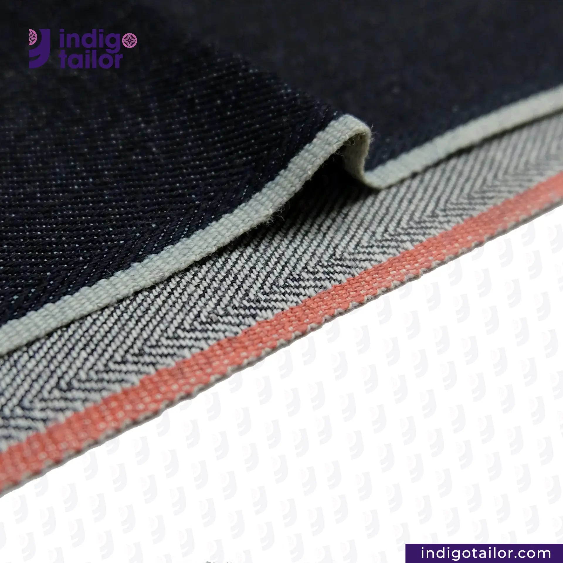 Close-up of DEEP INDIGO TWO COLORED EDGE SELVEDGE DENIM fabric with a visible brand logo, showing texture and color details.
