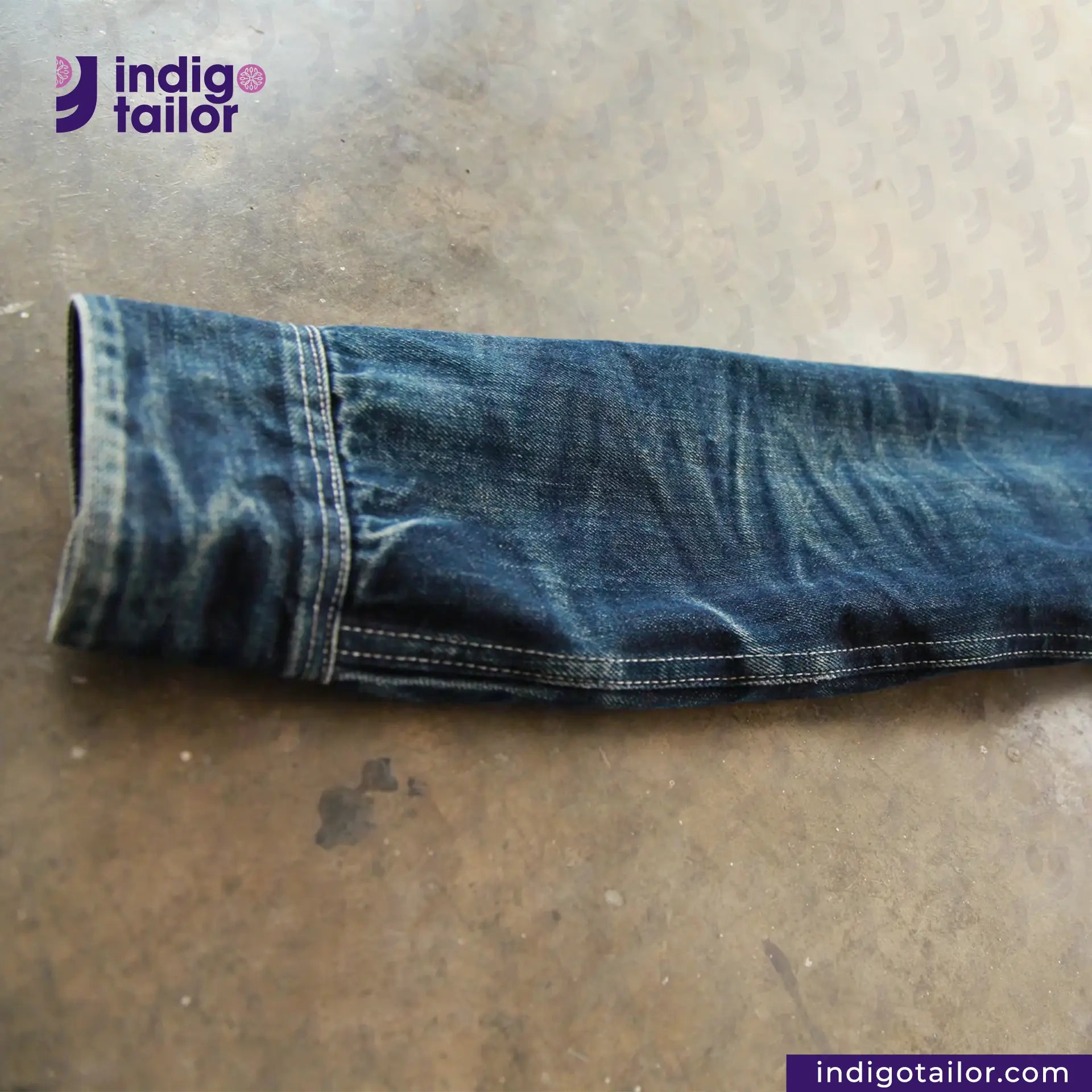 Rolled-up DENIM CHORECOAT on a metallic surface with 'indigotailor' branding.