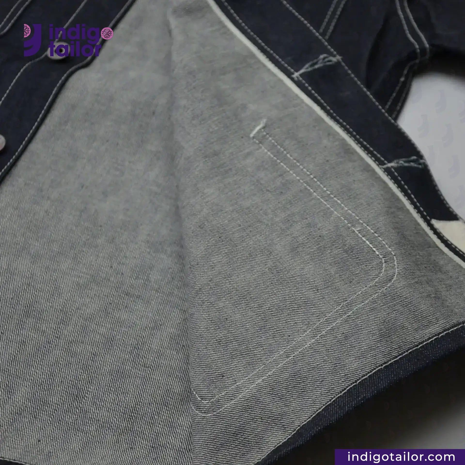 Close-up of DENIM CHORECOAT fabric with stitching detail, featuring the Indigo Tailor logo.