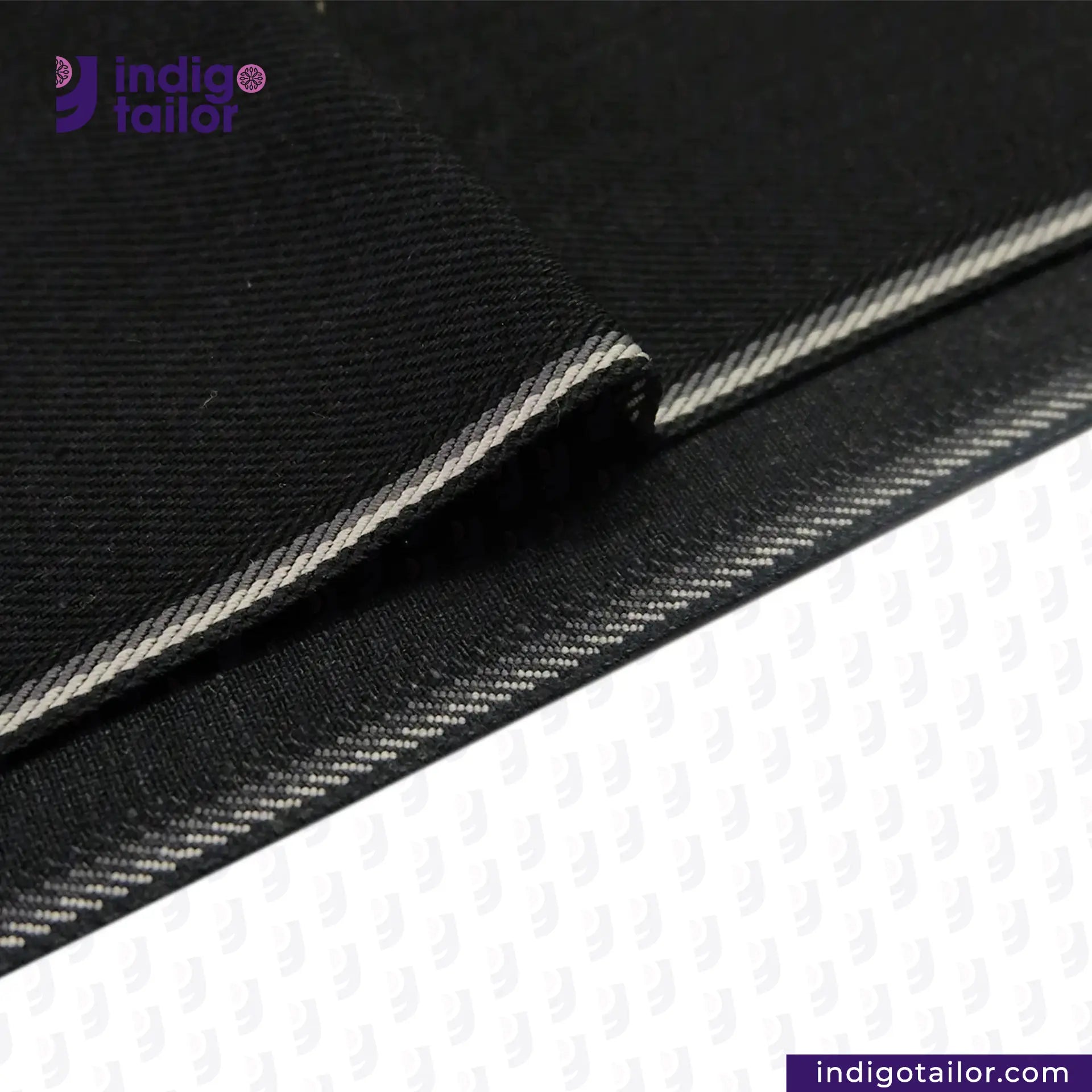 Close-up of DOUBLE BLACK OREO SELVEDGE DENIM fabric with white stitching on a white background, featuring the Indigotailor logo.