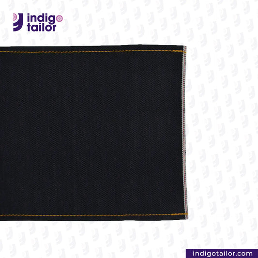 Close-up of DOUBLE BLACK STRETCH SELVEDGE DENIM fabric with yellow stitching on a white background, featuring the Indigotailor logo.