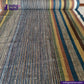 Roll of multicolored EARTH JACKET fabric with 'Indigotailor' branding.