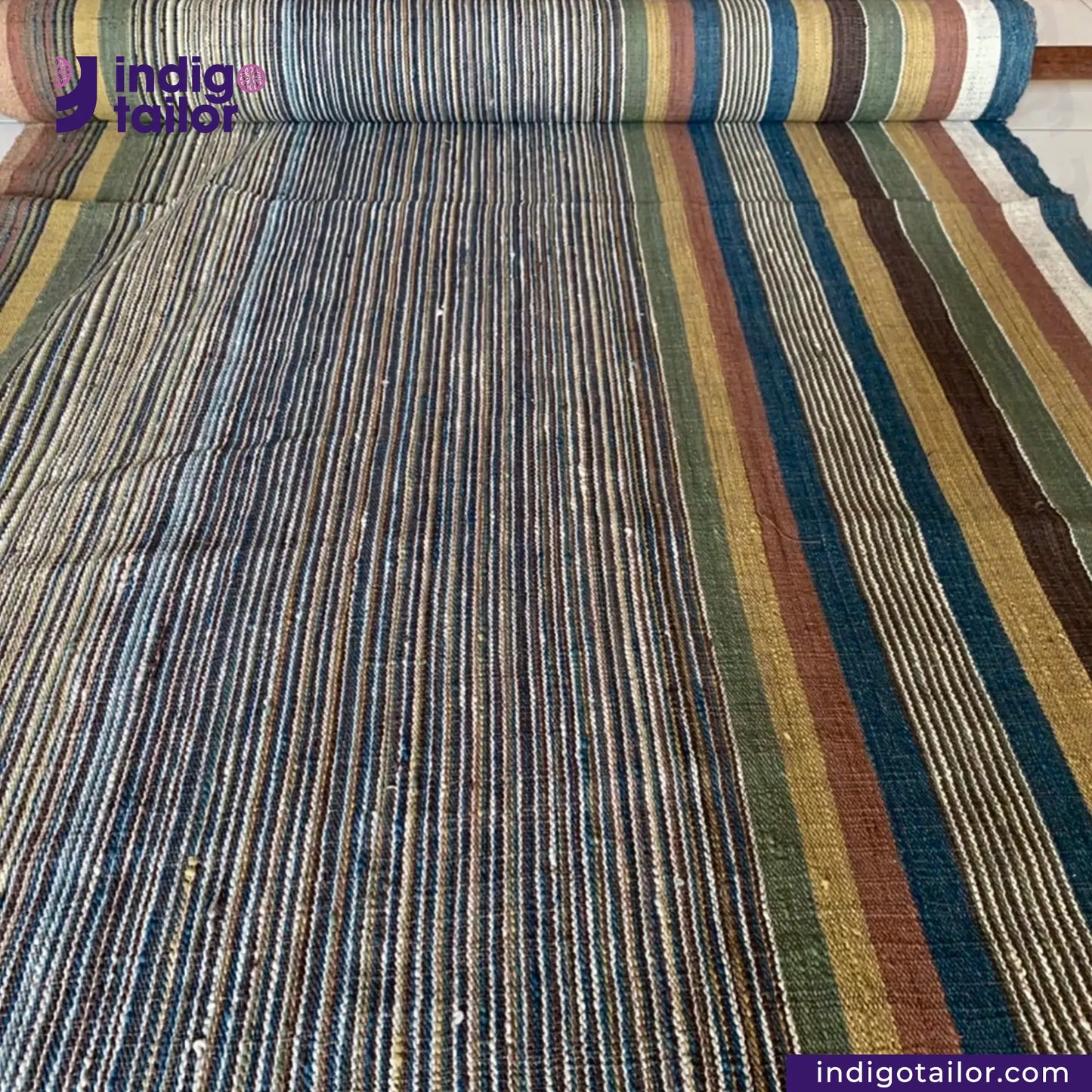 Roll of multicolored EARTH JACKET fabric with 'Indigotailor' branding.