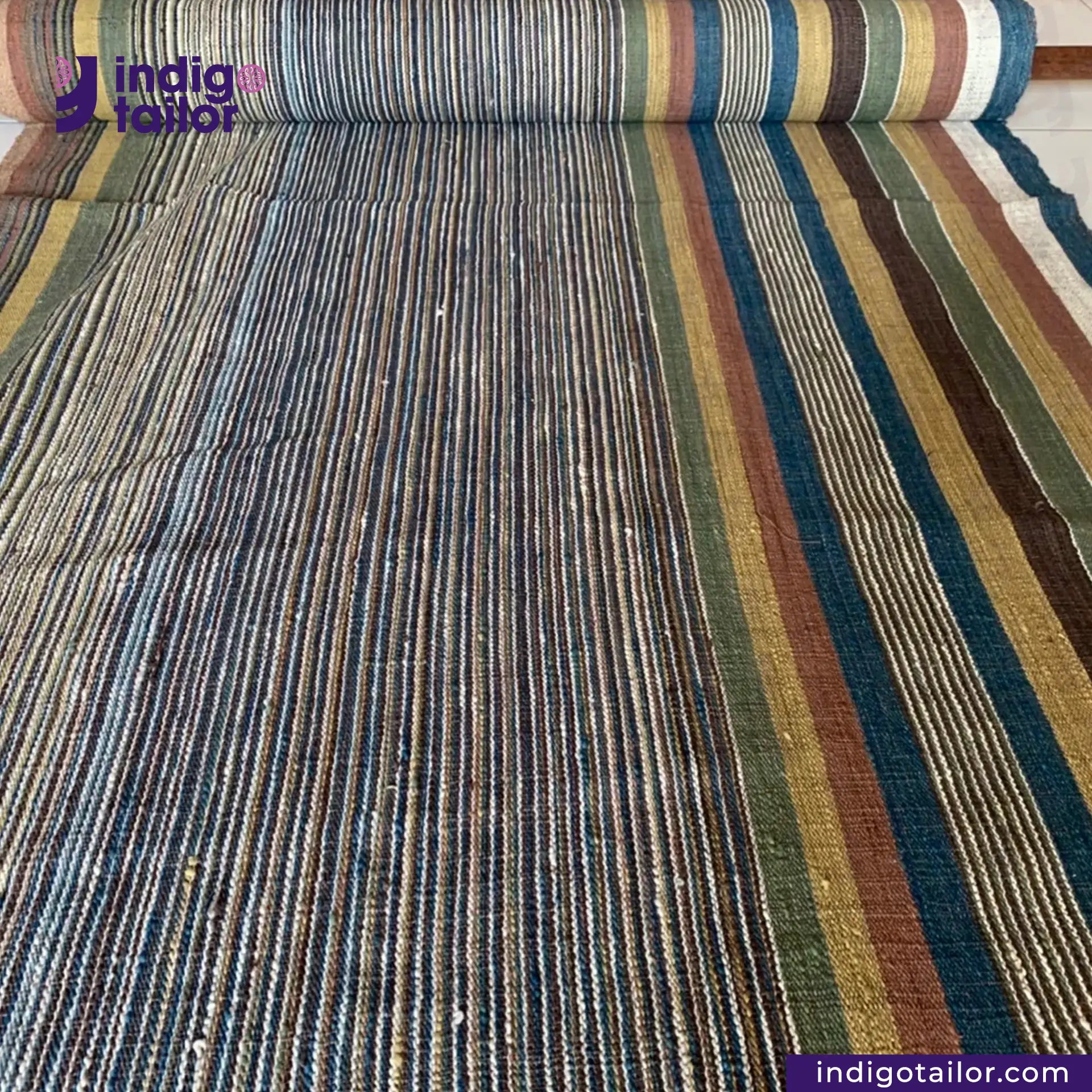 Roll of multicolored EARTH JACKET fabric with 'Indigotailor' branding.