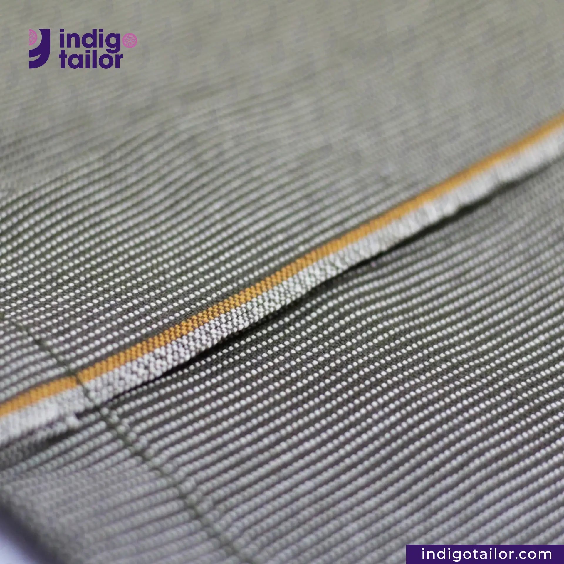 Close-up of EASY JACKET OLIVE WABASH ONE WASH with yellow stitching detail, featuring 'indigo tailor' logo.